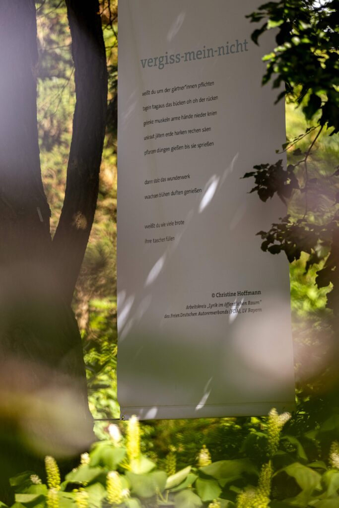 Ein großer Banner mit Gedicht-Titel vergiss-mein-nicht hängt an einem Baum. © Max Winkler